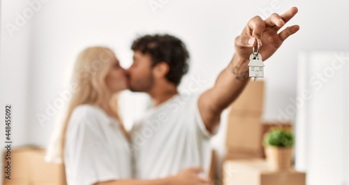 Young beautiful couple smiling happy holding key of new home.