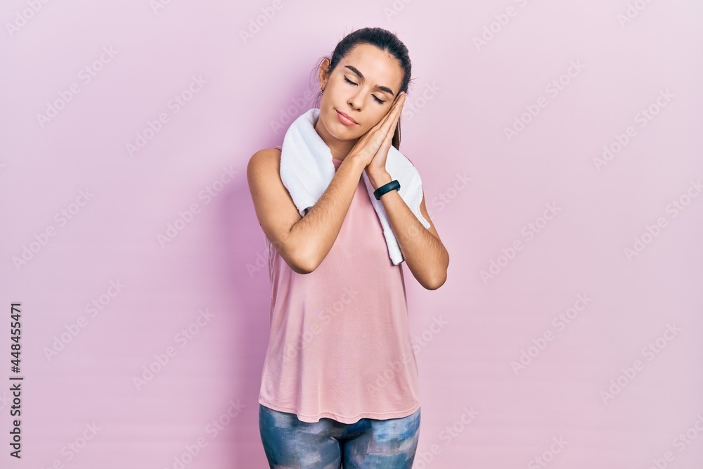 Young brunette woman wearing sportswear and towel sleeping tired dreaming and posing with hands together while smiling with closed eyes. Young brunette woman wearing sportswear and towel sleeping tired dreaming and posing with hands together while smiling with closed eyes.