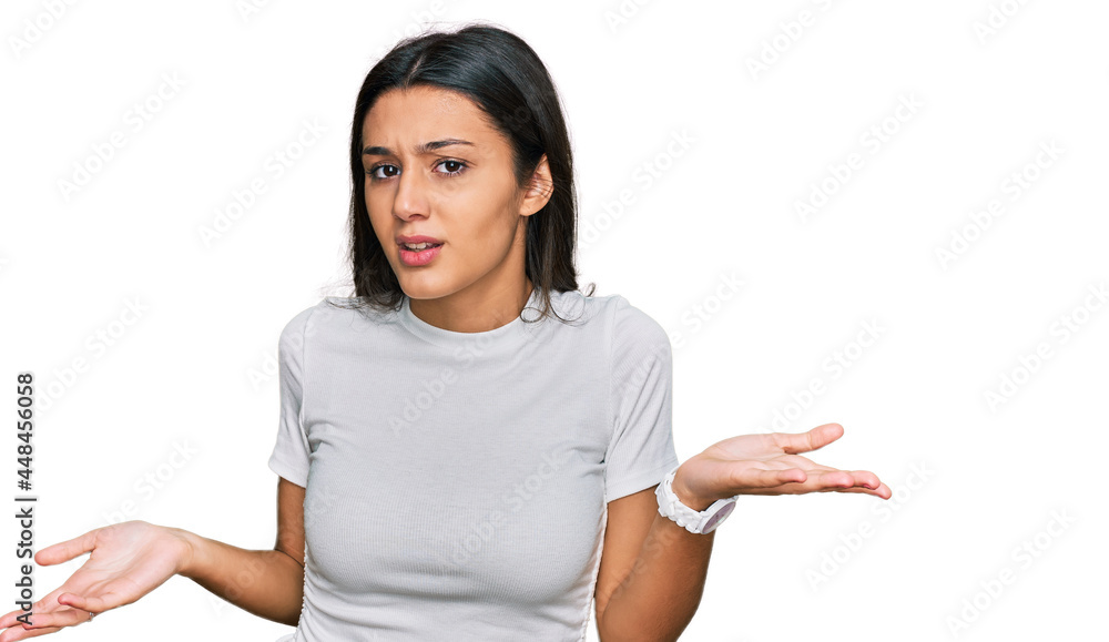 Young hispanic girl wearing casual white t shirt clueless and confused with open arms, no idea concept. Young hispanic girl wearing casual white t shirt clueless and confused with open arms, no idea concept.