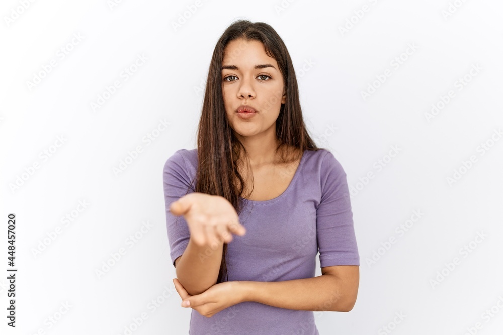 Young brunette woman standing by isolated background looking at the camera blowing a kiss with hand on air being lovely and sexy. love expression. Young brunette woman standing by isolated background looking at the camera blowing a kiss with hand on air being lovely and sexy. love expression.