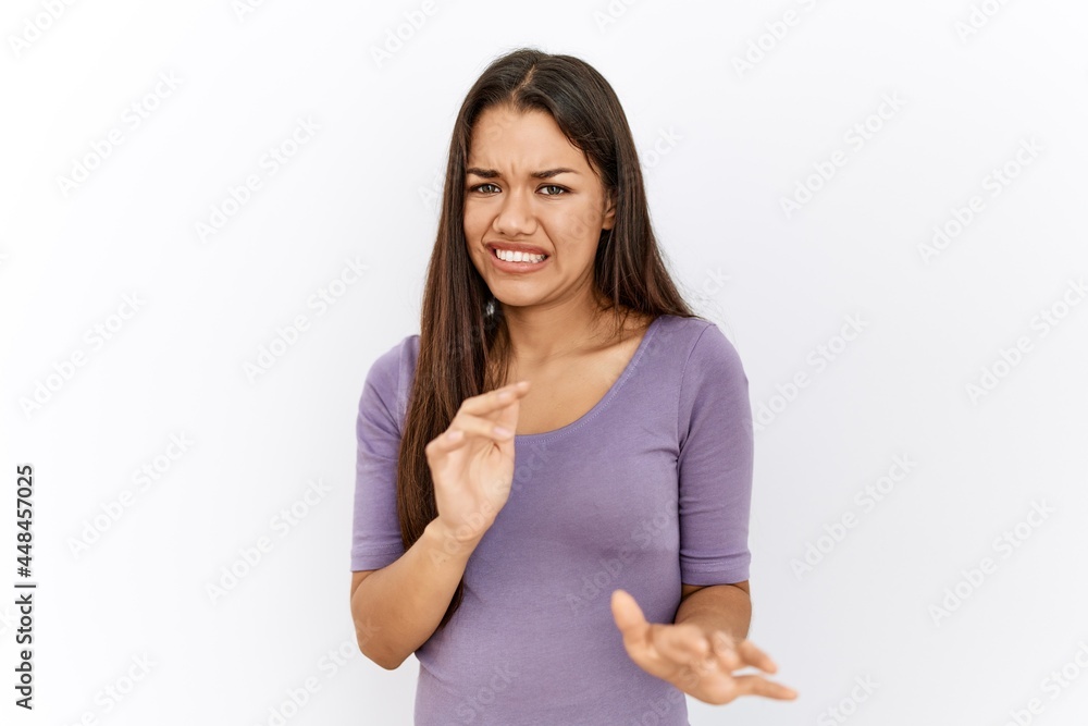 Young brunette woman standing by isolated background disgusted expression, displeased and fearful doing disgust face because aversion reaction. with hands raised Young brunette woman standing by isolated background disgusted expression, displeased and fearful doing disgust face because aversion reaction. with hands raised