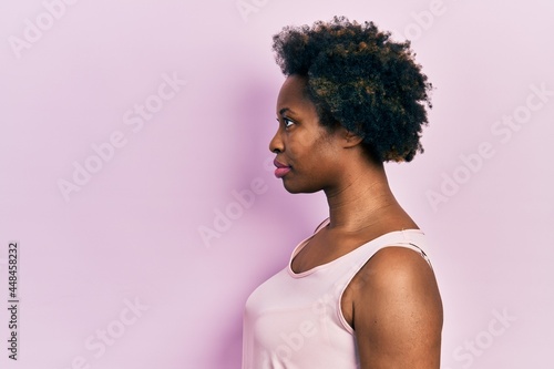 Young african american woman wearing casual sleeveless t shirt looking to side, relax profile pose with natural face with confident smile.