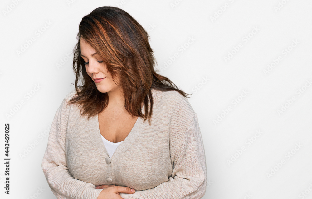 Young plus size woman wearing casual clothes with hand on stomach because indigestion, painful illness feeling unwell. ache concept.