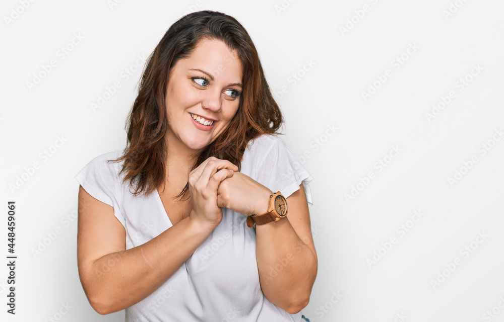 Young plus size woman wearing casual white t shirt laughing nervous and excited with hands on chin looking to the side Young plus size woman wearing casual white t shirt laughing nervous and excited with hands on chin looking to the side
