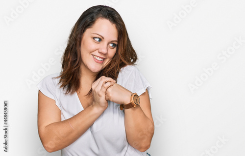 Young plus size woman wearing casual white t shirt laughing nervous and excited with hands on chin looking to the side © Krakenimages.com