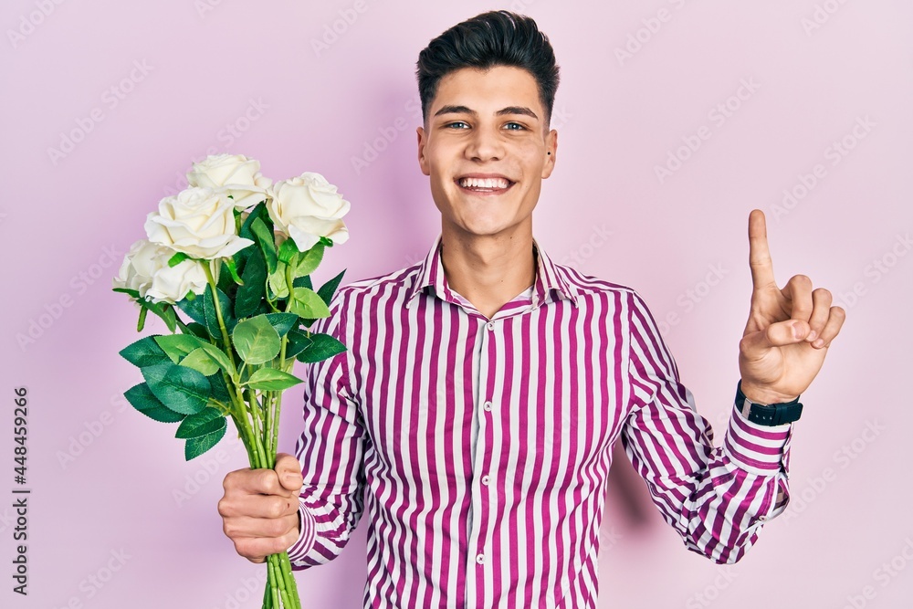 Young hispanic man holding flowers smiling with an idea or question pointing finger with happy face, number one Young hispanic man holding flowers smiling with an idea or question pointing finger with happy face, number one