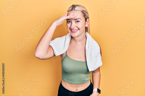 Young blonde girl wearing sportswear and towel very happy and smiling looking far away with hand over head. searching concept. © Krakenimages.com
