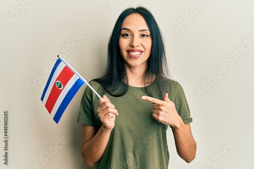 Young hispanic girl holding costa rica flag smiling happy pointing with hand and finger photo