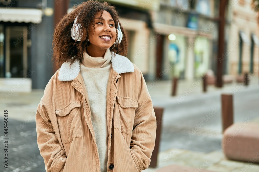 Fototapeta premium Young african american woman listening to music at the city.