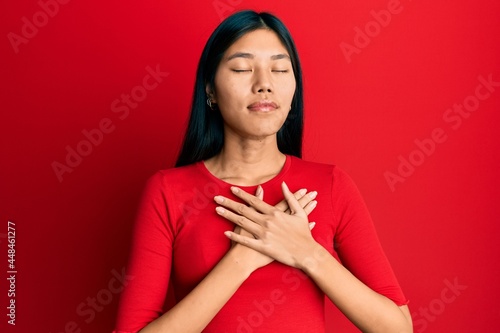 Young chinese woman wearing casual clothes smiling with hands on chest, eyes closed with grateful gesture on face. health concept.