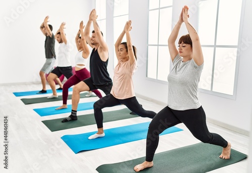 Group of young hispanic people concentrate training yoga at sport center.