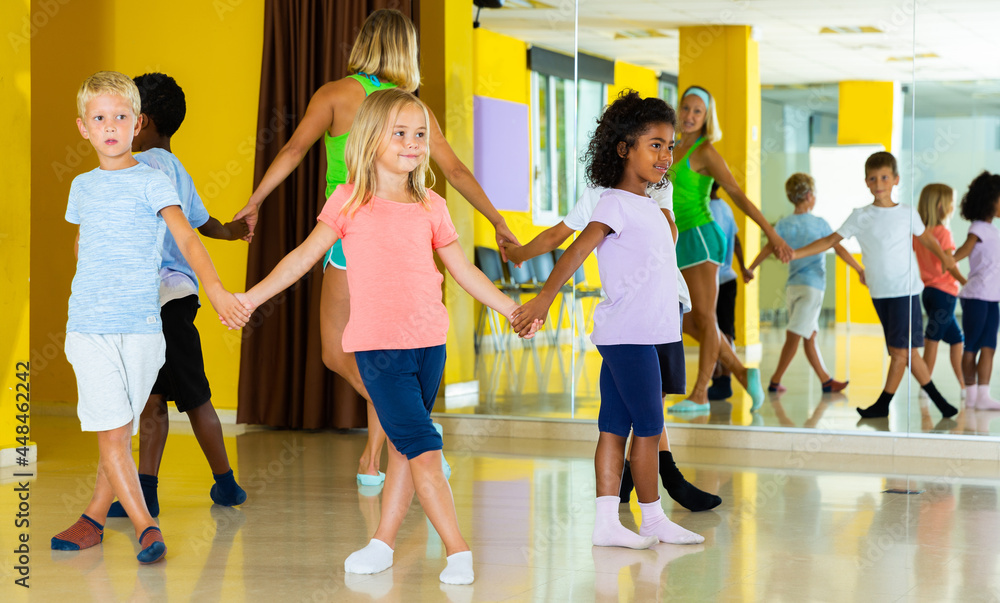 Happy kids and female teacher dancing together in studio at elementary school. High quality photo