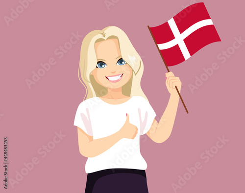 Young cheerful Danish woman with long blonde hair holding Denmark flag in casual clothes showing thumb up