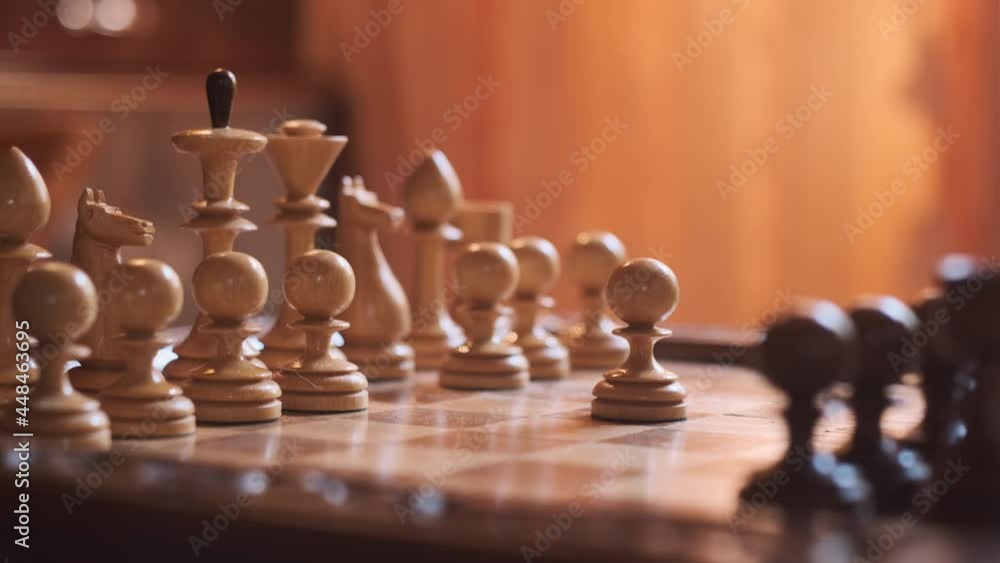 Pawn move on wooden chessboard. game of chess is like game of finance, one move can solve everything. white chess piece moves first. man moves figure with his hand. Pawn move on wooden chessboard. game of chess is like game of finance, one move can solve everything. white chess piece moves first. man moves figure with his hand.