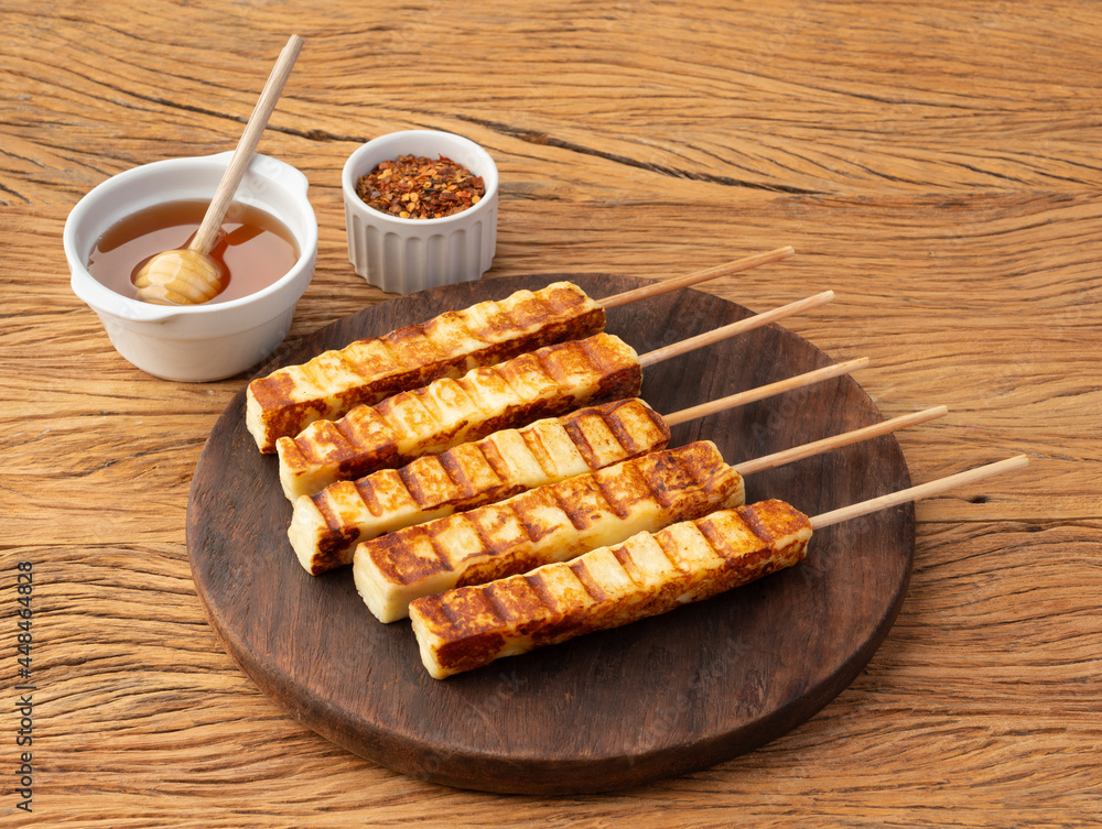 Ταπετσαρία Grilled Rennet or Coalho cheese on a wooden board with sugar syrup and pepper