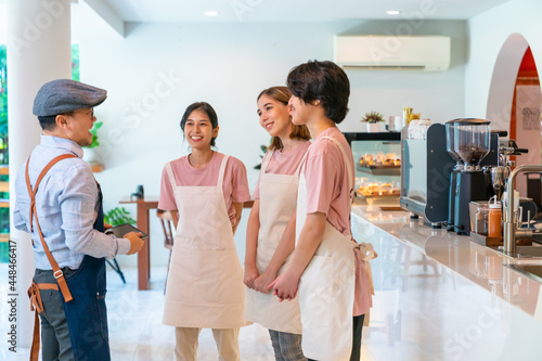 Billede på lærred Asian male coffee shop manager briefing man and woman staff team before working