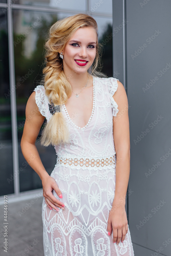 Fototapeta premium Beautiful blond bride in white wedding dress standing near mirror window outdoors.