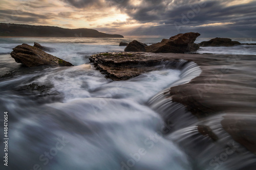 cascades flowing into the ocean from the rocks at the beach © Geoff