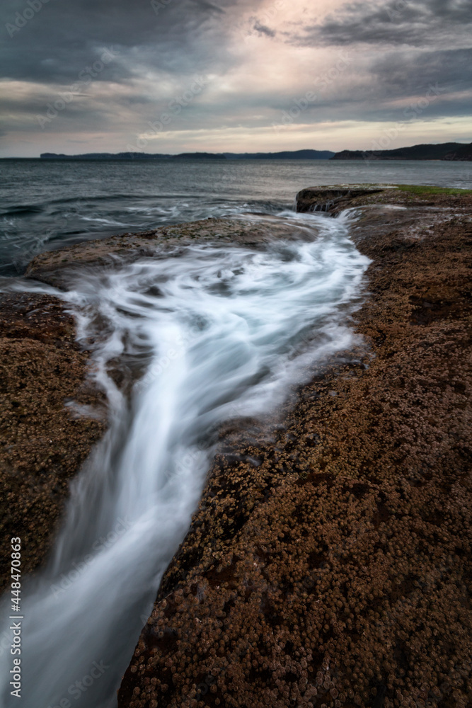 water flowing from the rocks out into the ocean along the coast water flowing from the rocks out into the ocean along the coast