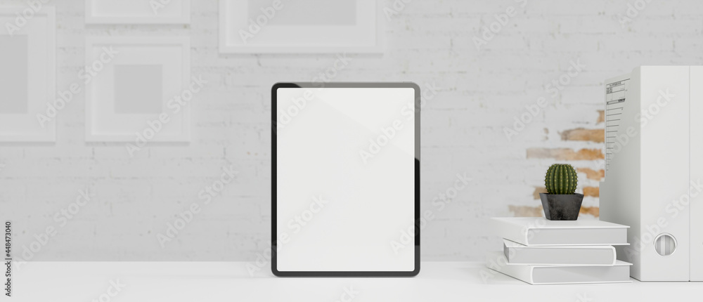 Smart digital tablet stand on white worktable with white brick wall, blank screen tablet mock up Smart digital tablet stand on white worktable with white brick wall, blank screen tablet mock up