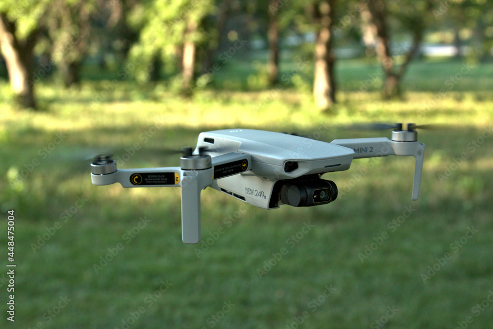 Late afternoon close up of a quad copter flying above the green grass and trees in the background Late afternoon close up of a quad copter flying above the green grass and trees in the background