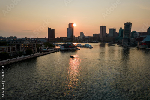 Fototapeta Naklejka Na Ścianę i Meble -  Aerial View of Baltimore City Inner Harbor at Sunset with Boat Passing in the Water