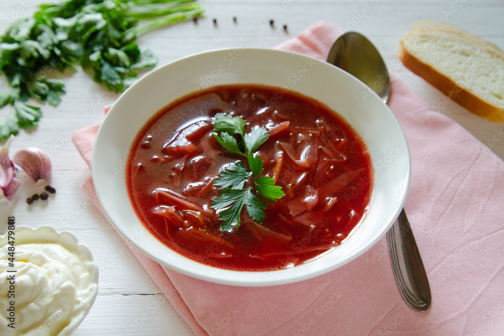 The national Russian and Ukrainian dish is red borscht with beetroot and cabbage. Served in white dishes on a light background The national Russian and Ukrainian dish is red borscht with beetroot and cabbage. Served in white dishes on a light background