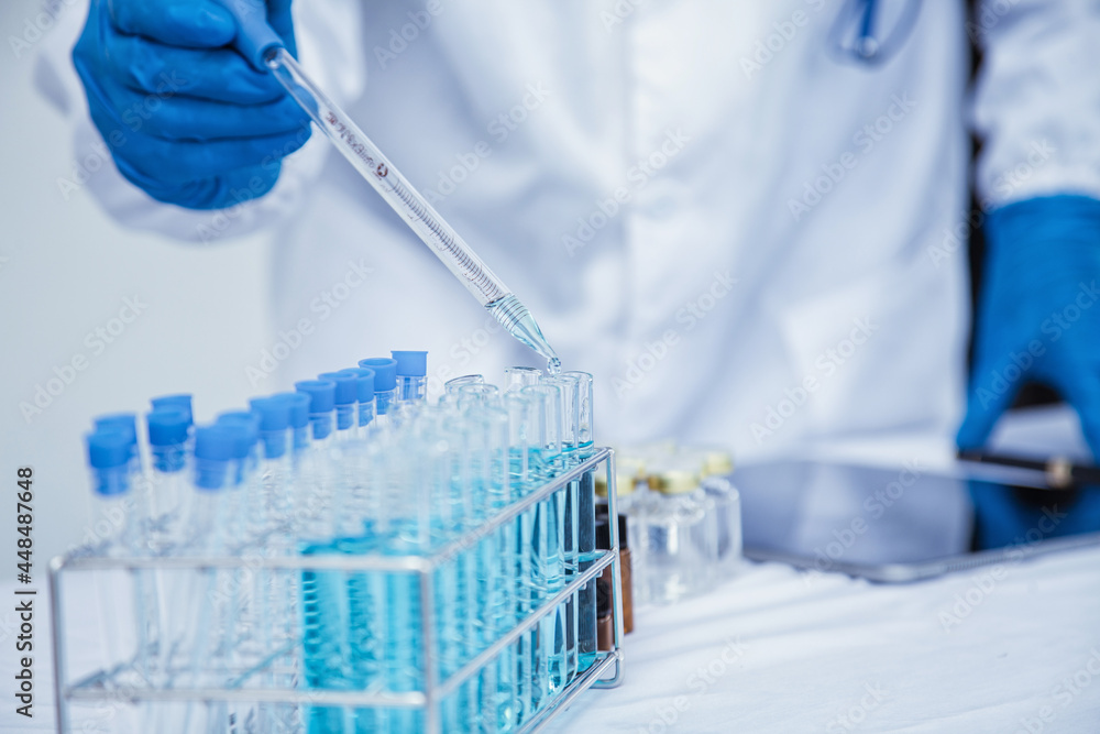 medical or scientific researcher researching and experimenting Multi-colored solution, vial and microscope In the laboratory or in the laboratory by wearing blue gloves and white clothing completely. medical or scientific researcher researching and experimenting Multi-colored solution, vial and microscope In the laboratory or in the laboratory by wearing blue gloves and white clothing completely.