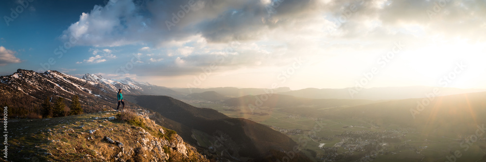 Panorama of girl watching the sunset in mountains