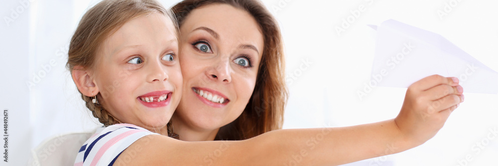 Blond smiling little girl make paper plane Blond smiling little girl make paper plane