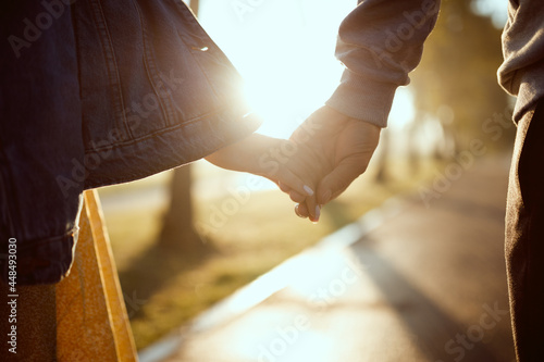 A guy and a girl hold hands against the background of the sun