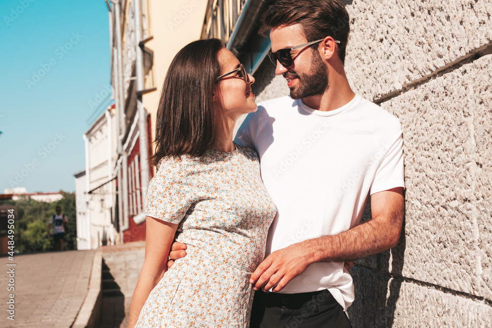 Naklejka premium Smiling beautiful woman and her handsome boyfriend. Woman in casual summer clothes. Happy cheerful family. Female having fun. Couple posing on the street background in sunglasses.Hugging each other