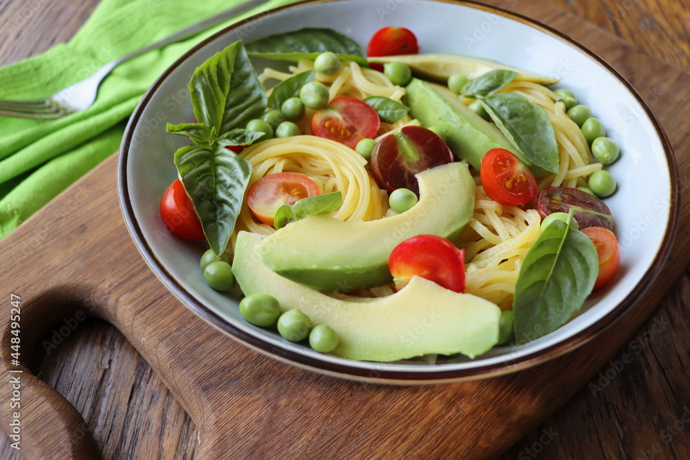Pasta salad with green peas, avocado, cherry tomatoes and basil on rustic wooden background. Top view Pasta salad with green peas, avocado, cherry tomatoes and basil on rustic wooden background. Top view
