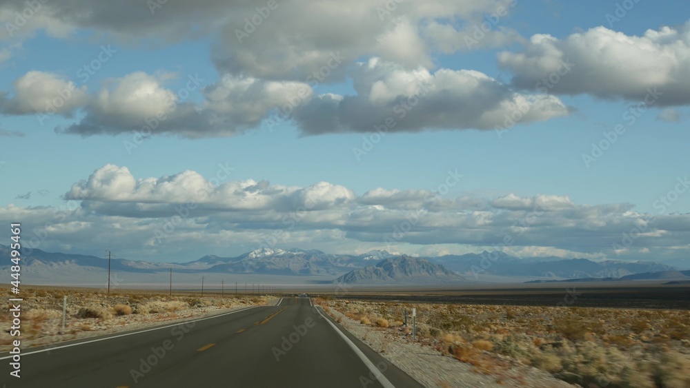 Road trip, driving auto from Death Valley to Las Vegas, Nevada USA. Hitchhiking traveling in America. Highway journey, dramatic atmosphere, clouds, mountain and Mojave desert wilderness. View from car Road trip, driving auto from Death Valley to Las Vegas, Nevada USA. Hitchhiking traveling in America. Highway journey, dramatic atmosphere, clouds, mountain and Mojave desert wilderness. View from car