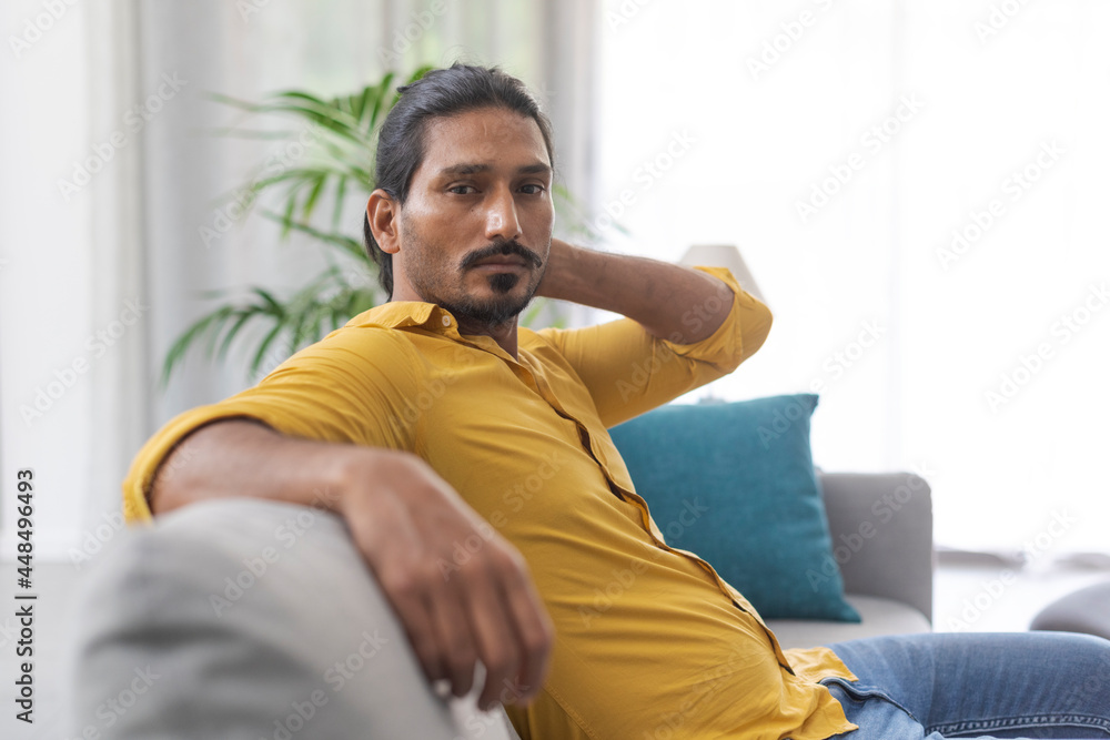 Confident man sitting on the sofa and looking at camera