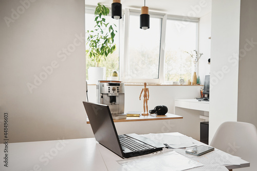 Open laptop on the kitchen table in home interior. Home office, remote work. Freelancer workplace