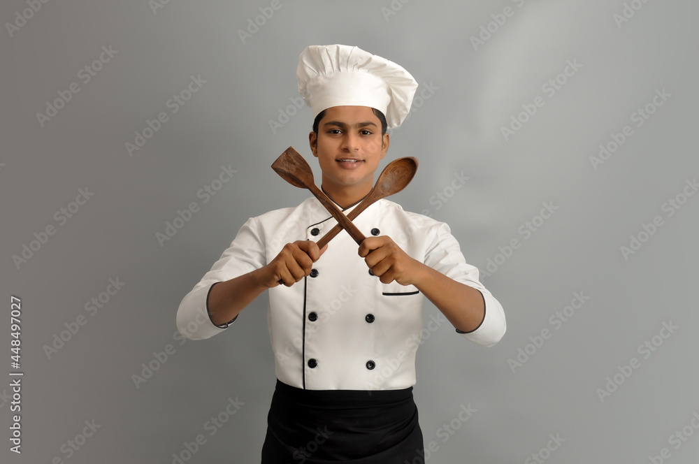Happy male chef dressed in uniform holding wooden spoon Happy male chef dressed in uniform holding wooden spoon
