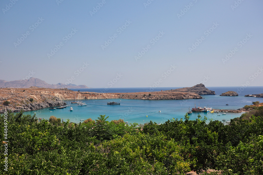 Greek Panorama of Lindos Bay in Rhodes. Beautiful View of Aegean Sea, Rock, Green Tree and Blue Sky in Greece.