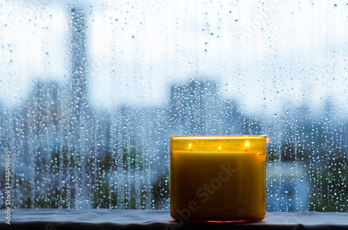 Burning aroma candle puts near by window that have rain drop in monsoon season. Zen and relax concept. photo