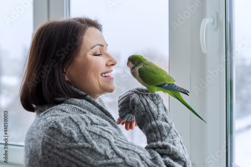 Canvas Print Middle aged woman and parrot together, female bird owner talking looking at gree