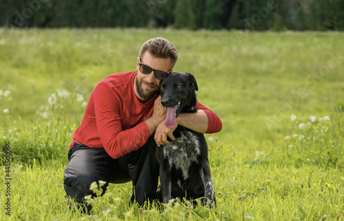 Caucasian man, 30 years old, is hugging his happy dog in outdoors.