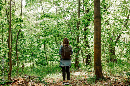 Young woman with backpack in a mixed forest Beskidy in Poland in spring time.
