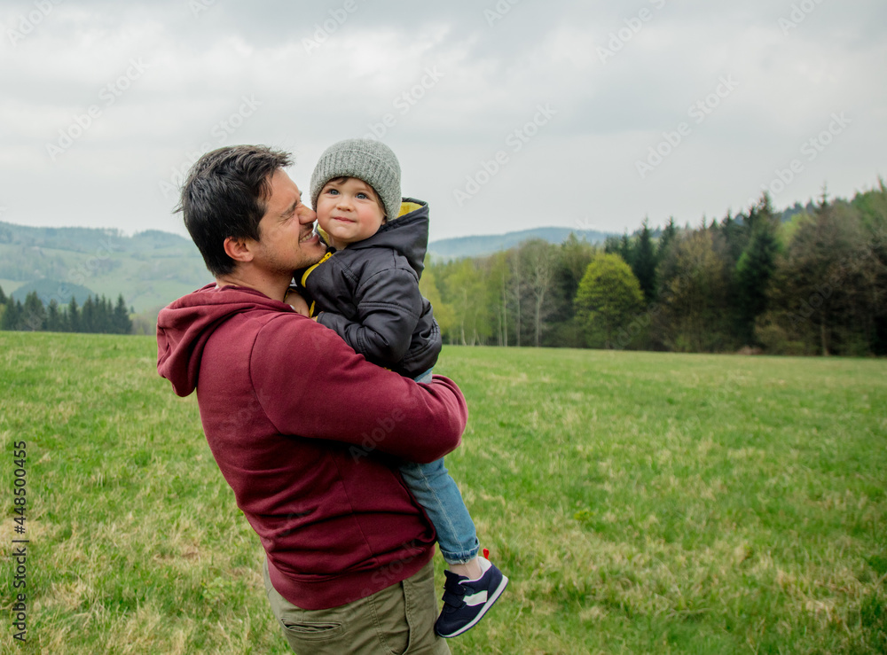 Father and son hugging on vacation on spring time meadow in mountains