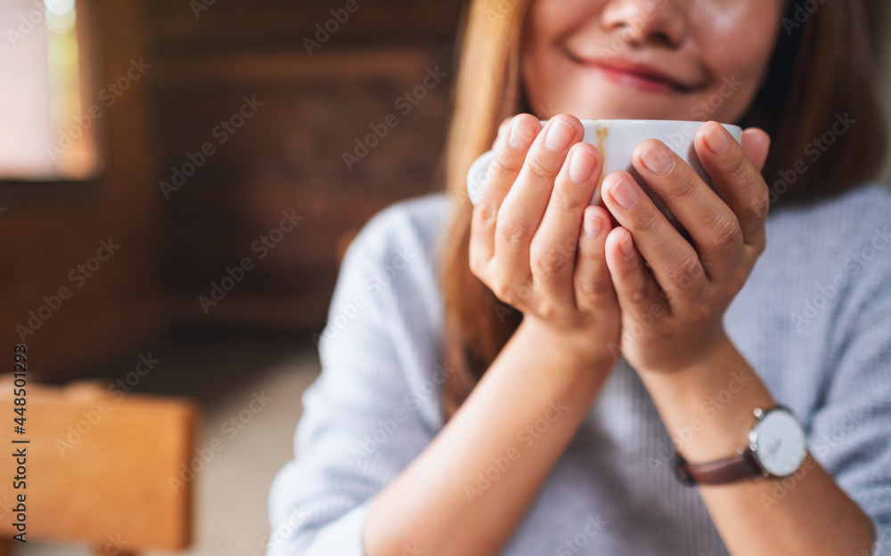 Closeup image of a young asian woman smelling and drinking hot coffee Closeup image of a young asian woman smelling and drinking hot coffee