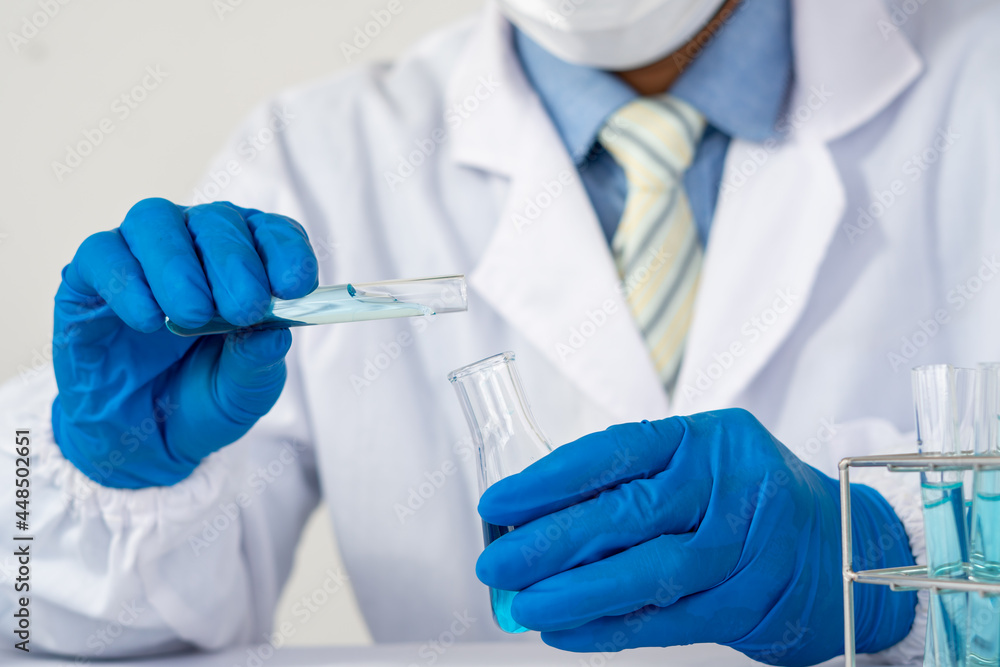 Biochemistry laboratory research, Scientist or medical in lab coat holding test tube with using reagent with drop of color liquid over glass equipment working at the laboratory. Biochemistry laboratory research, Scientist or medical in lab coat holding test tube with using reagent with drop of color liquid over glass equipment working at the laboratory.