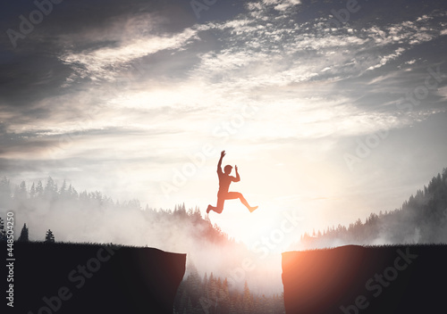 Man jumping between cliffs at sunset. photo