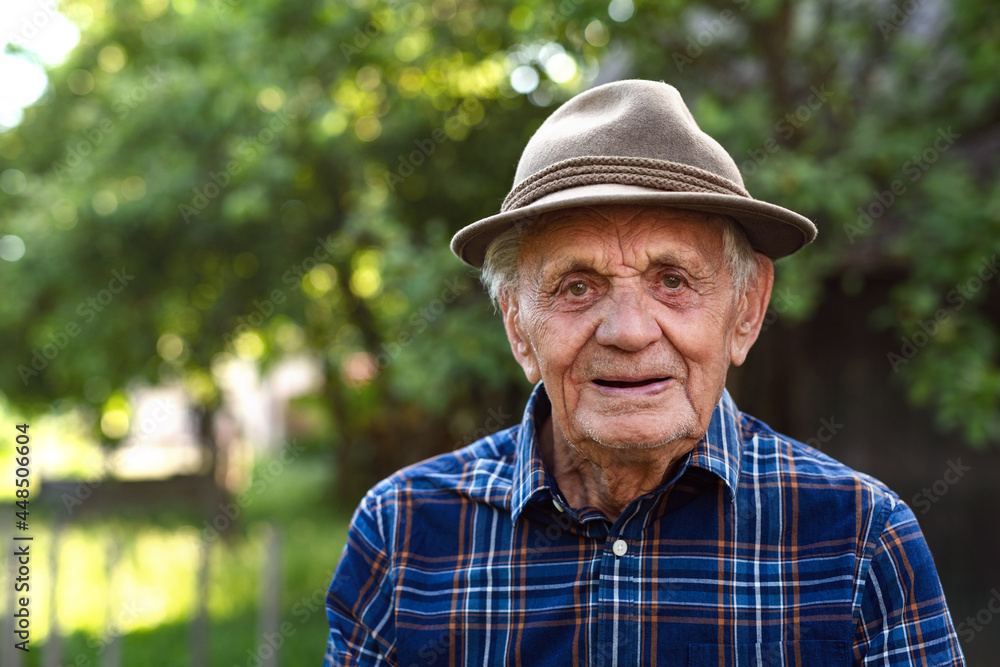 Portrait of elderly man standing outdoors in garden, looking at camera. Portrait of elderly man standing outdoors in garden, looking at camera.
