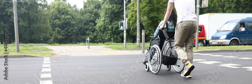 Man helping disabled woman to move in wheelchair on road