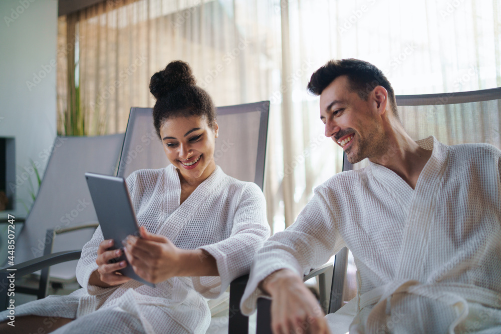 Portrait of young couple relaxing in spa resort, using tablet. Portrait of young couple relaxing in spa resort, using tablet.