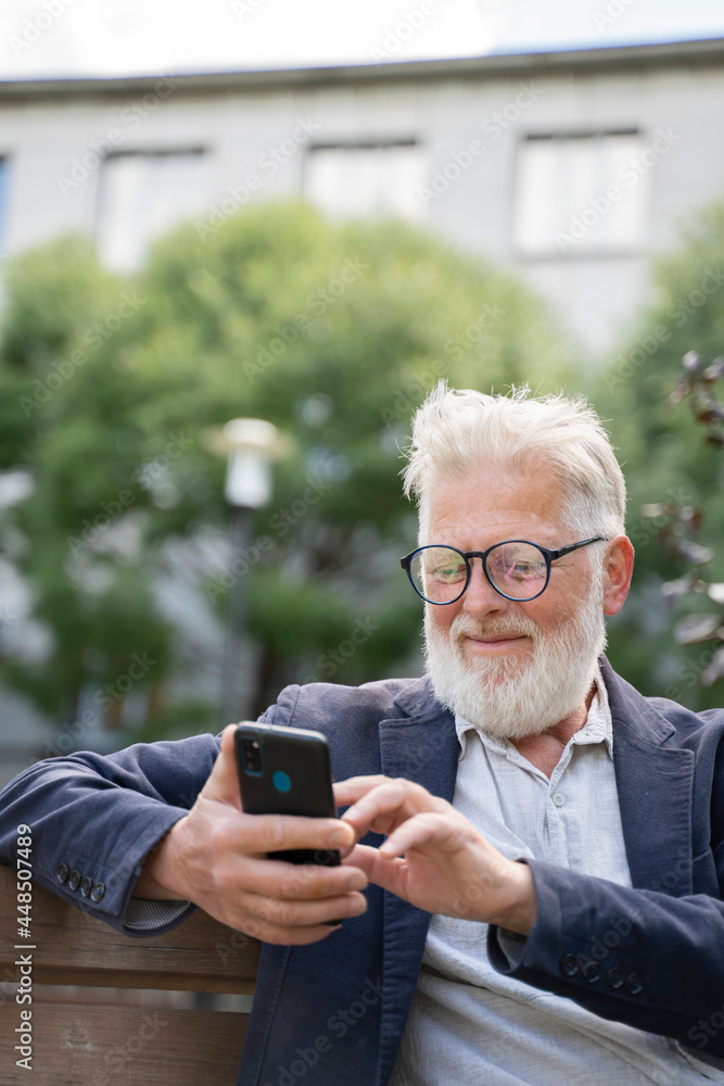 an elderly retired man is working on the phone sitting on the street an elderly retired man is working on the phone sitting on the street